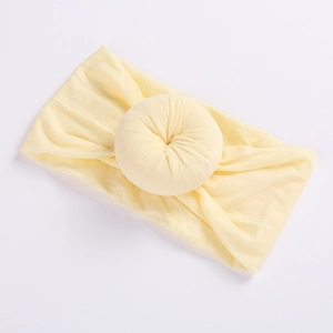 Detail of soft pale yellow nylon baby headband featuring a sweet donut-shaped knot design