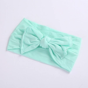 Close-up of mint green wide baby headband featuring a soft knit texture and large bow detail