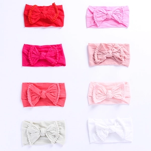 Close-up of 8 colors baby nylon headbands with large bows and pom-pom trim detail