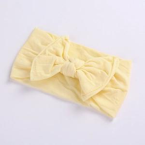 Close-up of light yellow baby headband with soft elastic fabric and large bow detail