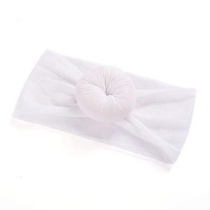 Detail showing soft white nylon baby headband with a donut-shaped knot and knit texture