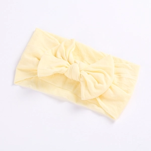 Detailed view of a soft pale yellow baby nylon headband with a large decorative bow