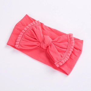 Detail view of pink elastic nylon baby headband with a large pom-pom lace bow