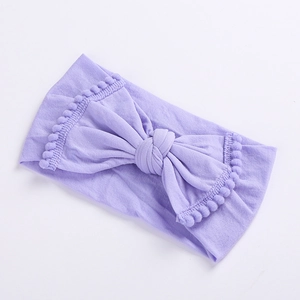 Close-up of light purple baby headband showing soft knit texture and pom-pom edge