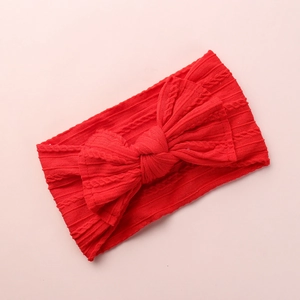 Detailed view of red knitted nylon baby headband with textured braid and bow