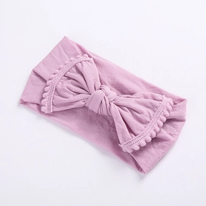 Detailed texture of baby elastic headband with soft pom-pom fringe and big bow