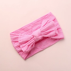 Detail of baby headband featuring pink cable knit texture and large bow decoration