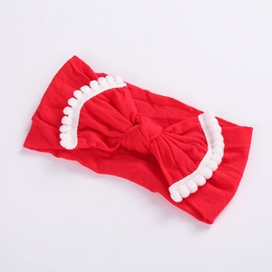 Close-up of red elastic nylon headband with big bow and white pom-pom fringe detail