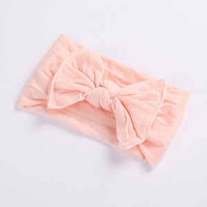 Detailed view of baby headband featuring a soft light pink oversized bow on nylon band