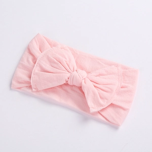 Macro detail of soft light pink baby headband featuring a large knitted cotton bow