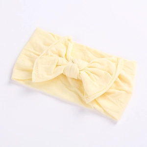 Close-up of a pale yellow baby headband with a large decorative soft fabric bow