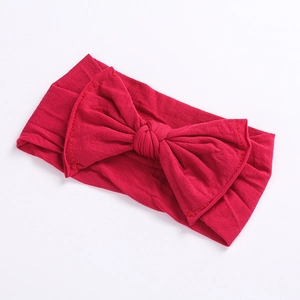 Detail of red wide bow headband featuring soft fabric texture and neat stitching details