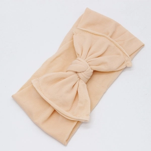 Detailed texture of seamless nylon baby headband with a large bow in champagne color