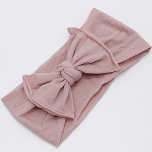 Detail of baby headband with a large layered bow in soft dusty pink knitted fabric