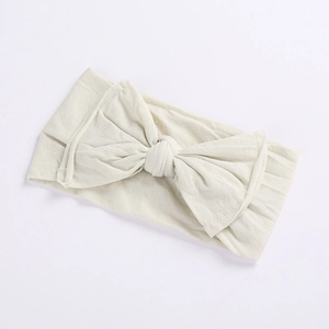 Elastic baby headband with a large cream bow in soft knit fabric for comfortable wear