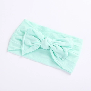Soft mint green baby headband featuring a large hand-knotted bow on elastic fabric