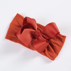 Detail of soft nylon orange baby headband with a large red ribbed grosgrain bow