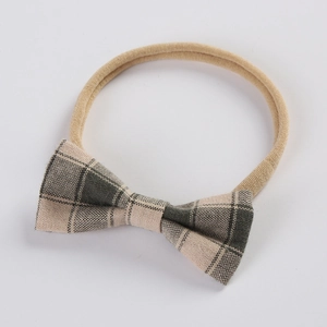 Détail d'un bandeau bébé avec nœud en lin à carreaux gris sur ruban en nylon souple