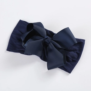 Detail view of navy blue elastic nylon headband with large ribbed grosgrain ribbon bow