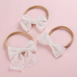 Lot de trois bandeaux pour bébé avec nœuds en dentelle blanche et nylon souple sur fond rose