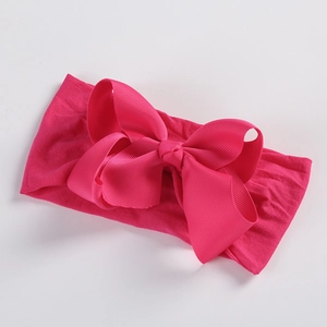 Detail of soft nylon infant headband with a large bright pink ribbed grosgrain bow