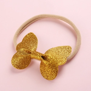 Vue détaillée du bandeau bébé en nylon élastique avec un nœud doré à paillettes