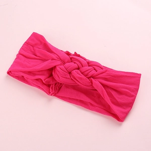 Détail du bandeau en nylon élastique fuchsia avec un design à nœud torsadé pour bébés