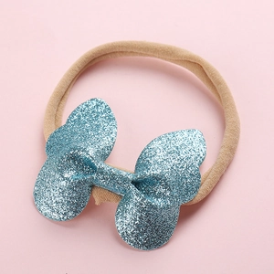 Détail d'un nœud à paillettes bleues sur un bandeau élastique rose pour bébé et enfant