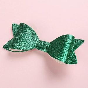 Detailaufnahme einer glitzernd grünen Schleifen-Haarspange mit funkelnder Textur