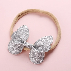 Bandeau pour bébé avec un grand nœud à paillettes argentées sur un élastique beige