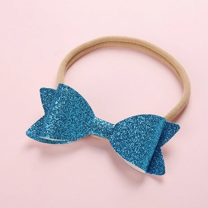 Macro view of sparkly blue sequin bow attached to a soft nylon seamless headband for babies