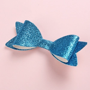 Makroaufnahme einer geschichteten blauen Glitzerschleife für Kinder auf rosa Hintergrund