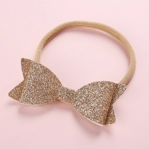 Close-up of golden glitter bow on ultra-soft nude nylon headband for babies