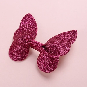 Close-up of a 3D pink glitter butterfly hair clip showing texture and metallic sparkle