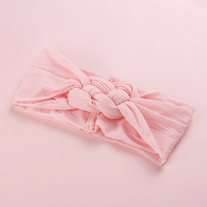 Détail d'un bandeau large en nylon rose doux avec un nœud tressé central élégant