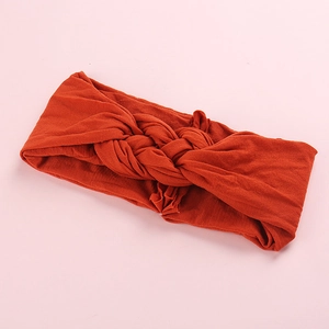 Texture détaillée du tricot d'un bandeau d'hiver orange foncé avec un nœud torsadé