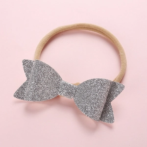 Close-up of baby nylon headband featuring a large silver sequin bow on a pink background
