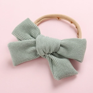 Détail du nœud en velours côtelé vert menthe sur un bandeau bébé en nylon doux