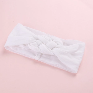 Détail du bandeau pour bébé en tricot blanc doux sur fond rose pastel uni