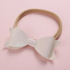 Detail of baby headband featuring a soft nylon band and a glittery pink sequin bow charm