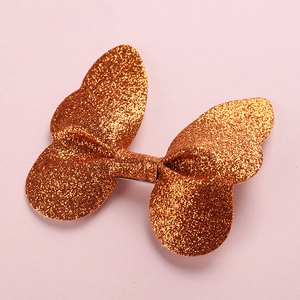 Detail of glitter butterfly hair clip showing shiny bronze texture and metal base