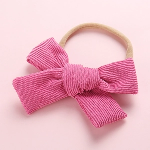 Détail macro du nœud en velours rose et du bandeau élastique en nylon pour bébé