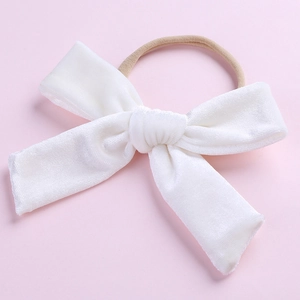 Détail d'un nœud en velours blanc avec bandeau en nylon élastique sur fond rose tendre
