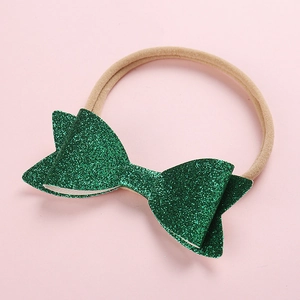 Detailed view of shiny green sequin bow on a soft nude nylon headband for infants