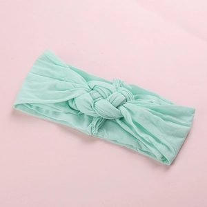 Détail du bandeau pour bébé en nylon vert menthe avec un design de nœud central complexe