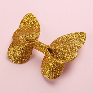 Macro shot of 3D glittery golden butterfly hair clip showing detailed sparkle texture