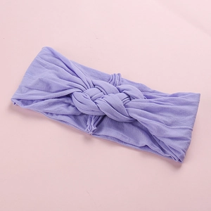 Gros plan d'un bandeau lilas pour bébé en nylon avec détail de nœud torsadé doux