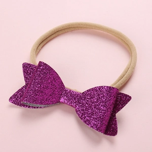 Detail of baby headband featuring a large purple sequin bow and soft nylon band