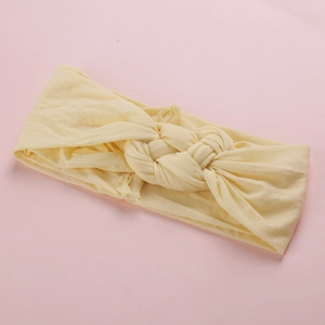 Détail d'un bandeau bébé jaune doux à nœud montrant la texture du tissu élastique