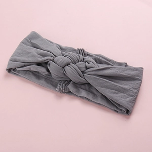 Gros plan détaillé du bandeau bébé gris en nylon élastique avec un design à nœud croisé
